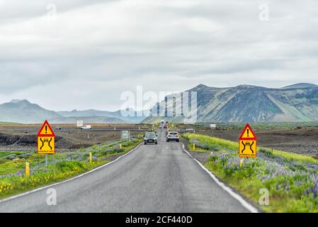 Vik, Islande - 14 juin 2018 : panneaux colorés pour le pont étroit en Islande avec champ de fleurs et voitures passant dans la circulation sur le ring Road trip Banque D'Images