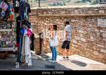 Assisi, Italie - 29 août 2018 : village de la ville d'Ombrie avec une femme dans un petit magasin vendeur de kiosque vendant des cadeaux souvenirs exposés Banque D'Images