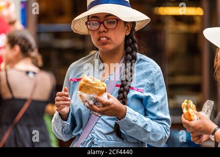 Florence, Italie - 30 août 2018: Femme jeune touriste mangeant le fameux sandwich dans la rue de Florence en été avec bokeh flou fond Banque D'Images