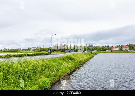 Reykjavik, Islande - 19 juin 2018 : lac de Tjornin ou Reykjavikurtjorn dans le centre-ville de la capitale avec de l'eau sur une journée et une route nuageux et couvert Banque D'Images