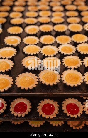 De dessus de petites pâtisseries fourrées de gelée de fruits doux et placé sur des plateaux métalliques dans la boulangerie Banque D'Images