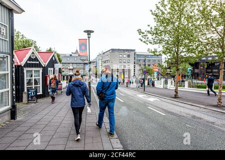 Reykjavik, Islande - 19 juin 2018: Gens touristes couple de marche en arrière sur le trottoir de rue dans le centre-ville par magasins boutiques restaurants avec des signes i Banque D'Images