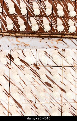 Vue de dessus des morceaux de délicieux chocolat blanc et brun gâteaux décorés de crème et de sauce sur table dans la boulangerie Banque D'Images