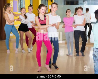 Groupe de pratique d'interpolations de mouvements vigoureux jive dans un studio de danse avec entraîneur féminin Banque D'Images