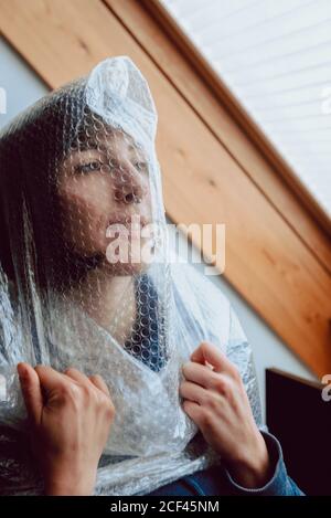 Femme effrayée essayant de se libérer tout en s'emmêlant dans le film à bulles Banque D'Images