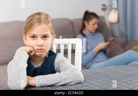 Petite fille offensé à cause de sa mère ne fait pas attention à elle et using smartphone Banque D'Images