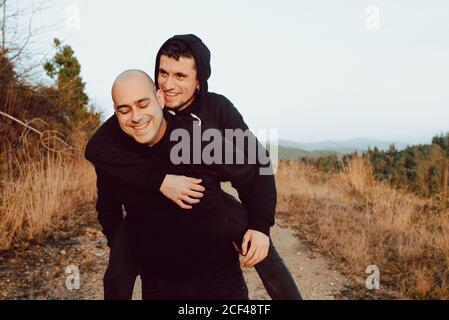 Heureux couple homosexuel ayant le plaisir sur la route entre les plantes sur montagne et ciel bleu Banque D'Images