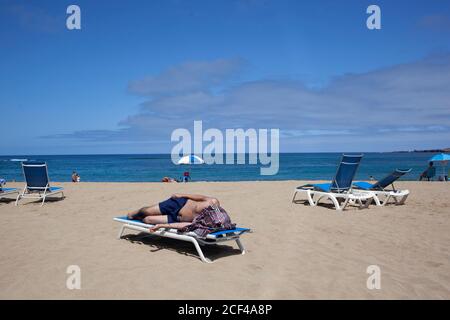 03 septembre 2020, Espagne, Las Palmas de Gran Canaria: Un homme allongé sur une chaise longue se protège du soleil avec un T-shirt sur la plage de Las Canteras. En raison de l'augmentation du nombre de nouvelles infections de corona, le gouvernement allemand a maintenant émis un avertissement de voyage pour les îles Canaries - et donc pour l'ensemble de l'Espagne. Photo: Manuel Navarro/dpa Banque D'Images