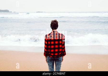 Femme debout sur le sable humide sur la plage Banque D'Images