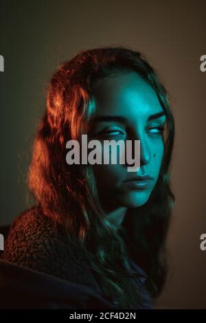 Focalisée mystique jeune femme à cheveux longs roulant les yeux en studio sur fond sombre Banque D'Images