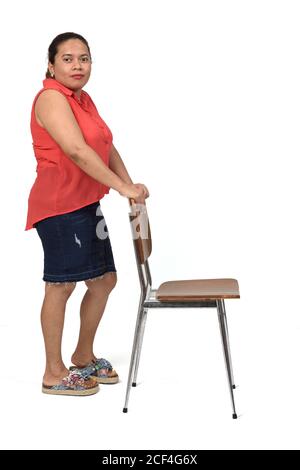 portrait complet d'une latinwoman avec jupe jouant avec un chaise sur fond blanc Banque D'Images