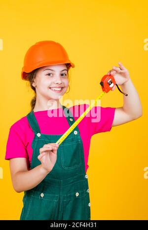 longueur. ouvrier de construction avec mètre ruban. Mignon enfant en tant que travailleur de la construction. Enfant répare la maison. Enfance heureuse. Mètre-ruban en métal auto-rétractable. Petite fille utilisant un mètre ruban. Banque D'Images