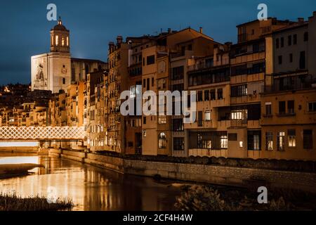 Charmant paysage de rivière qui coule le long de l'église et des maisons en soirée à Gérone, Catalogne, Espagne Banque D'Images