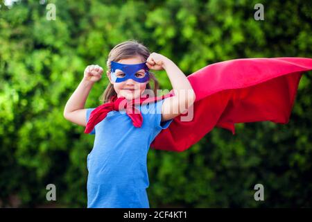 Super-héros petite fille sur fond vert en extérieur. Enfance, succès et concept de puissance Banque D'Images