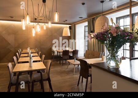 Lampe élégante qui brille au-dessus de petites tables et de chaises confortables restaurant confortable Banque D'Images