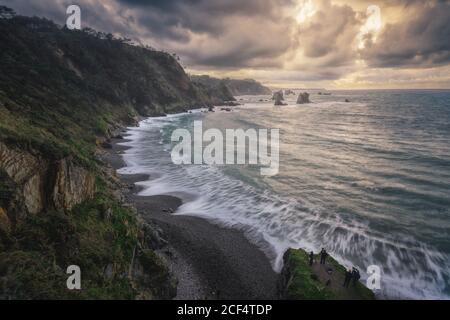 Vue pittoresque sur la crique spectaculaire entourée de falaises majestueuses fond de ciel lumineux avec nuages pluvieux Banque D'Images