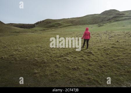 Femme anonyme appréciant le paysage magnifique de l'Irlande du Nord pendant le voyage tout en marchant sur le sol rocheux Banque D'Images