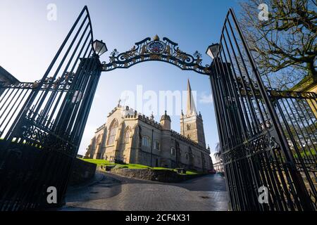 Depuis le dessous de la cathédrale Saint-Colombs par une entrée en fer ouverte porte avec barres et éléments décoratifs contre le ciel bleu Journée de printemps ensoleillée à Derry en Irlande du Nord Banque D'Images