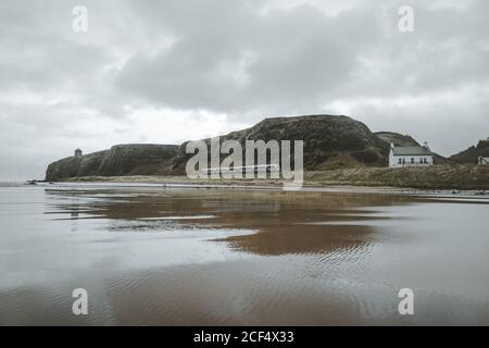 Paysage pittoresque avec le temple de Mussenden situé sur la falaise en pierre à Le littoral de l'Irlande du Nord et les vagues de la mer de tempête s'écrasant contre les rochers avec ciel gris nuageux en arrière-plan Banque D'Images