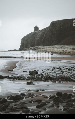 Paysage pittoresque avec le temple de Mussenden situé sur la falaise en pierre à Le littoral de l'Irlande du Nord et les vagues de la mer de tempête s'écrasant contre les rochers avec ciel gris nuageux en arrière-plan Banque D'Images