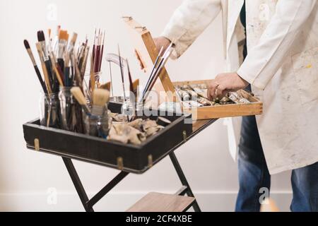 Artiste senior debout dans l'atelier de maison et de choisir des peintures Banque D'Images