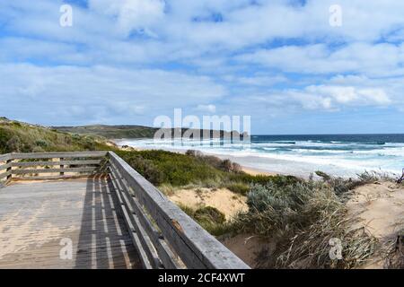 Une plate-forme d'observation en bois surplombe la plage de Cape Woolamai sur Phillip Island. L'herbe pousse du sable et l'océan est de couleur bleu vif. Banque D'Images