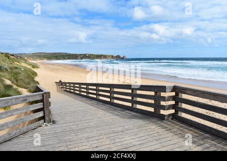 Une promenade en bois mène à la plage déserte de surf de Cape Wolamai dans le parc naturel de Phillip Island. Vagues se brisant sur la plage de sable doré. Banque D'Images