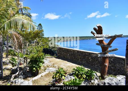 Un panneau indique la route vers Sydney, New York et Tokyo au sommet des falaises de Jokin sur Lifou, en Nouvelle-Calédonie. La mer de Corail bleue est visible derrière vous. Banque D'Images