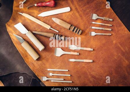 Outils de fabrication sur cuir de vache naturel dans l'atelier de personnalisation. Vue de dessus. Banque D'Images