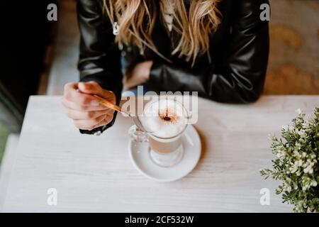 Courte inreconnaissable tendance belle femme blonde boire d'un verre de délicieux café mousseux Banque D'Images