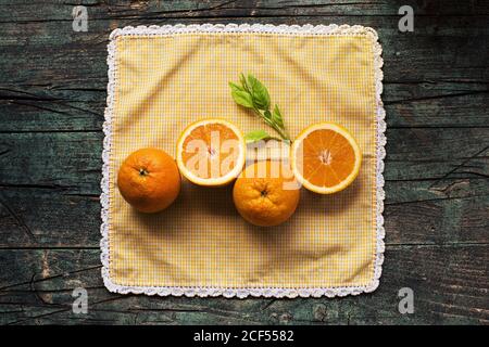 Moitiés d'oranges fraîches sur une table rustique sombre en bois sur fond sombre Banque D'Images