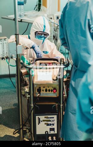 Médecin professionnel en uniforme de protection et gants de contrôle de l'équipement avant fonctionnement en salle d'opération dans une clinique moderne Banque D'Images