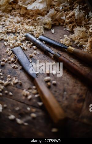 Grand angle de divers outils professionnels en métal de menuisier pour travailler avec des détails en bois placés sur l'établi parmi la sciure dans salle de travail Banque D'Images