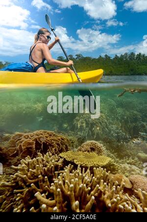 Vue latérale d'une jeune femme touriste voyageant en kayak lagon tropical au fond pittoresque Banque D'Images