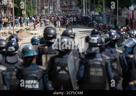 Les manifestants jettent des pierres vers la police pendant les affrontements.des centaines de dévots et de policiers anti-émeutes ont affronté lorsque les dévots ont essayé de lancer le cortège de Rato Machindanath. Le char fabriqué à Pulchowk de Lalitpur a été tenu pendant des mois en raison des ordres du gouvernement de ne pas célébrer les festivals annuels en raison de craintes sur la propagation du coronavirus. La statue est normalement tirée autour de la ville pendant un mois. Des policiers en tenue anti-émeute ont bloqué les manifestants lorsqu'ils ont déplacé le char, les faisant mouser avec du canon à eau et du gaz lacrymogène. Banque D'Images