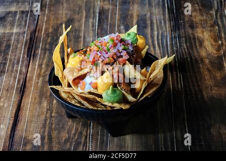 Grand angle de savoureux hors-d'œuvre à base de chips de maïs garni de guacamole et de sauce au fromage sur la table du restaurant Banque D'Images