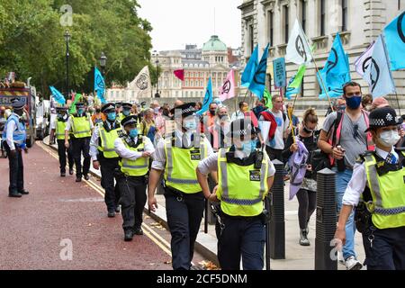 La police escorte les manifestants pendant la manifestation.devant les bâtiments du Trésor de HM, les manifestants du Carnaval de corruption de la rébellion d'extinction ont défilé vers Buckingham Palace mais ont été bloqués par la police au Mall. Les activistes exigent que les personnes au pouvoir prennent des mesures sur les questions climatiques et environnementales. Banque D'Images