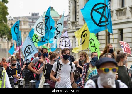 Les manifestants ont défilé avec des drapeaux pendant la manifestation.devant les bâtiments du Trésor de HM, les manifestants du Carnaval de corruption de la rébellion d'extinction ont défilé vers Buckingham Palace mais ont été bloqués par la police au Mall. Les activistes exigent que les personnes au pouvoir prennent des mesures sur les questions climatiques et environnementales. Banque D'Images