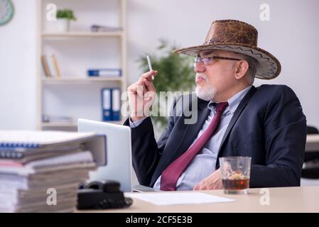 Drôle de vieux patron dans chapeau de cow-boy dans le bureau Banque D'Images