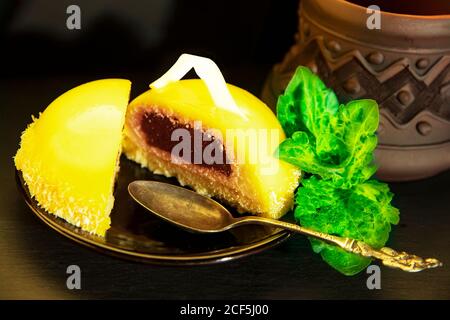 Délicieux biscuits mousse avec remplissage de baies sur une assiette sombre, une cuillère d'argent, des pétales de menthe et une tasse en céramique d'argile avec café sur une table dans un café. Traiteur Banque D'Images