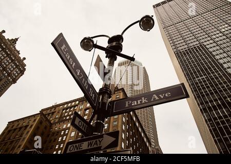 En dessous des panneaux de signalisation à sens unique sur le carrefour avec Hauts bâtiments modernes en arrière-plan dans la ville de New York Banque D'Images