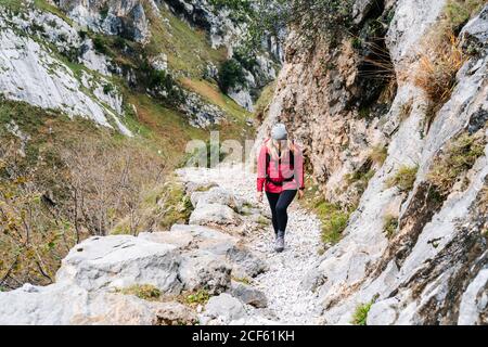 Active femme randonneur dans la veste rouge avec sac à dos lourd marchant vers le haut de la montagne dans les sommets de l'Europe, Asturies, Espagne Banque D'Images