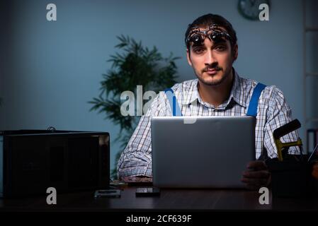 Jeune technicien répare l'ordinateur en atelier la nuit Banque D'Images