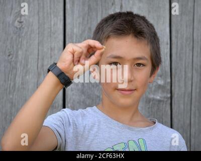 Mixte-race pré-adolescent garçon (est asiatique et caucasien) montre avec sa main droite le signe de la main chinoise pour le numéro 7 (photo série: Image no. 7 de 10). Banque D'Images