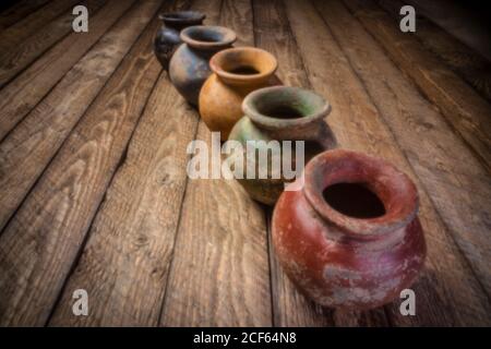 row os petits pots en argile grunge avec une finition de couleur rugueuse sur un bois abîmé, image de mise au point douce prise avec la caméra à trou d'épingle sans lensless Banque D'Images