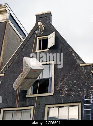 Le mobilier est soulevé à l'étage supérieur d'une maison à pignons à Amsterdam, Hollande, à l'aide d'une poulie extérieure et d'un système de corde. Banque D'Images