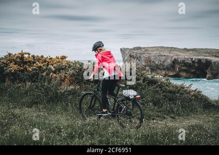 Vue arrière de la femme blonde dans un casque de protection à vélo sur fond de côte Banque D'Images