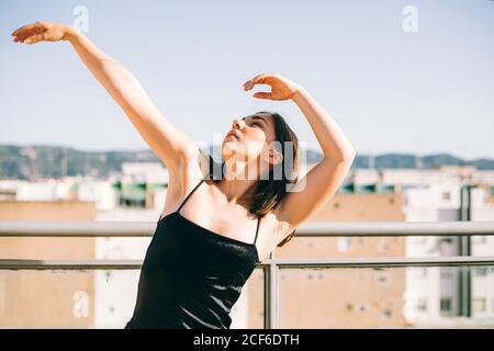 Danseuse gracieuse au moment de l'élément de représentation avec des étirements bras donnant sur la terrasse d'été sur fond de palmier arbres Banque D'Images