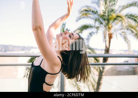 Danseuse gracieuse au moment de l'élément de représentation avec des étirements bras donnant sur la terrasse d'été sur fond de palmier arbres Banque D'Images