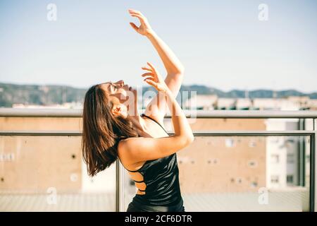 Danseuse gracieuse au moment de l'élément de représentation avec des étirements bras donnant sur la terrasse d'été sur fond de palmier arbres Banque D'Images